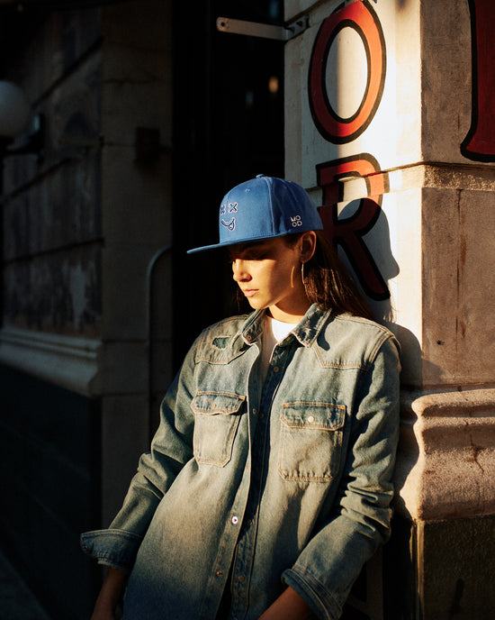 MOOD Caps model wearing XX OG baseball cap flat brim in loyal blue color, looking melancholy in new york
