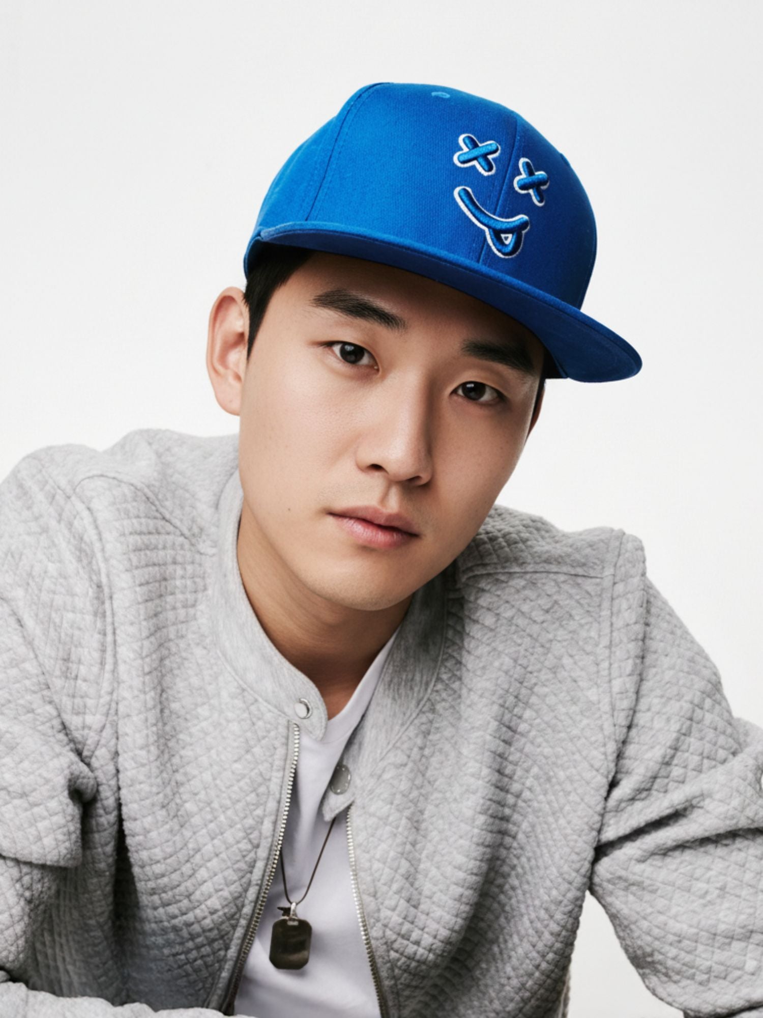 Person wearing a blue cap with a smiley face design on a light gray background