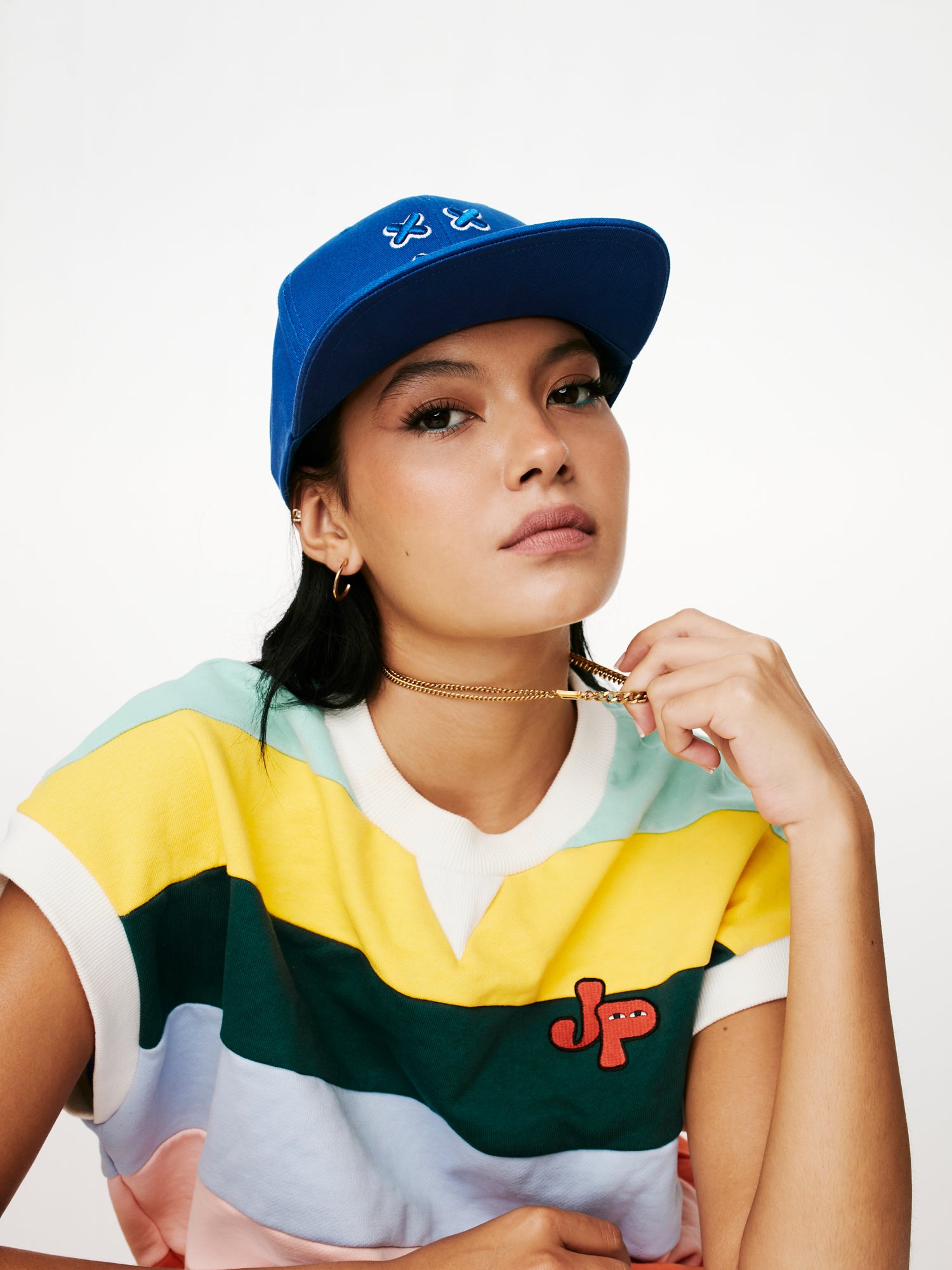 MOOD female model wearing XX OG flat brim baseball cap in loyal blue tugging her necklace